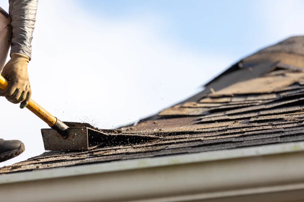 contractor uses shingle shovel to remove damaged roof parts