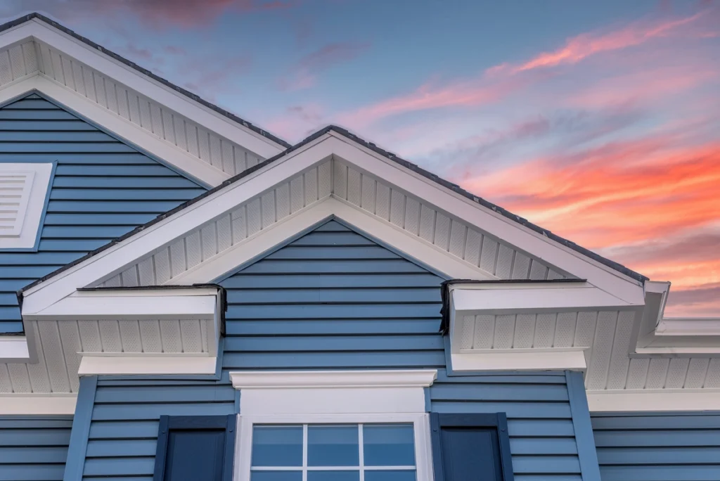 large house with brand new blue horizontal siding and sunset sky 