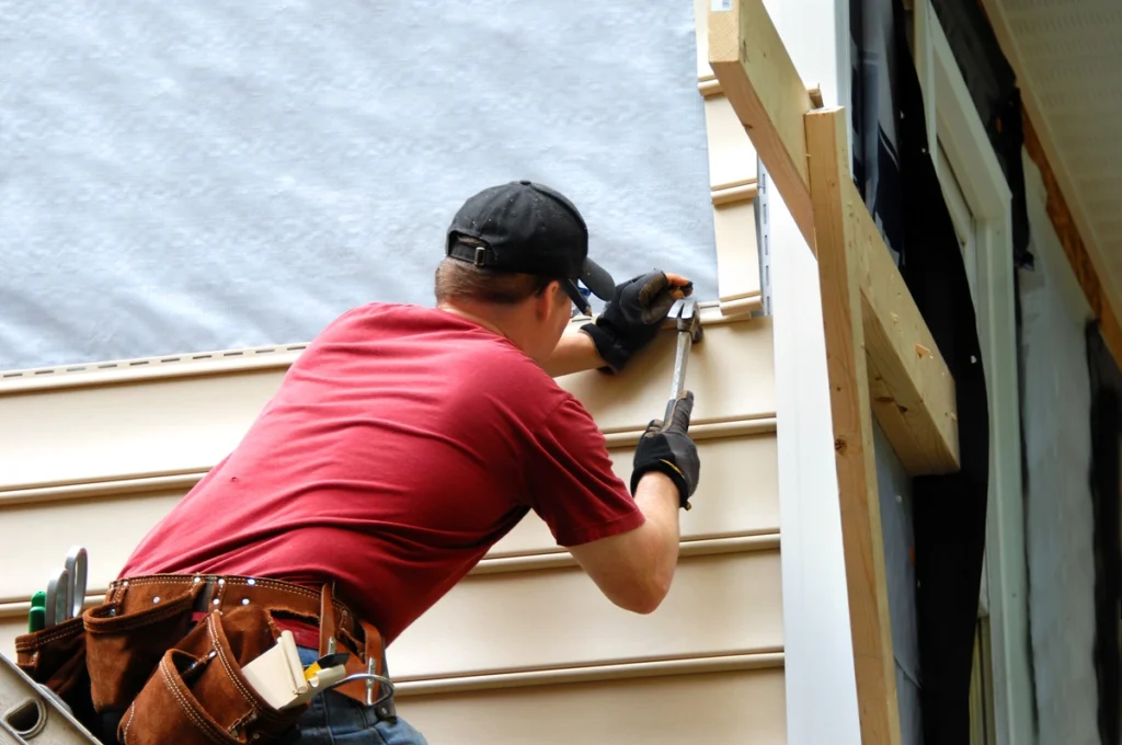 worker installing his house siding using hammer