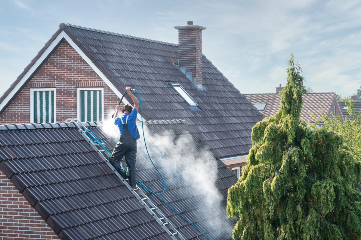 professional worker pressure washing the house roof