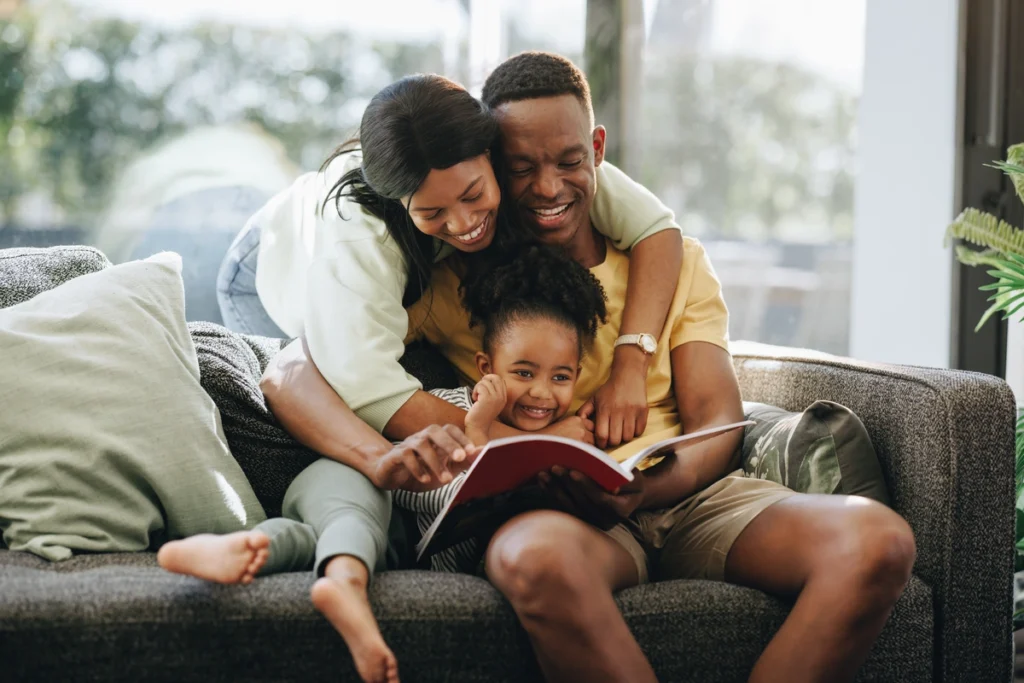 parents reading book to their daughter on the couch