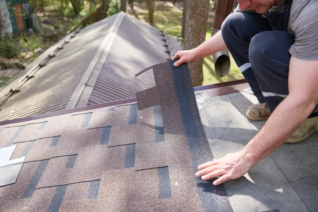 worker installing architectural shingles on the roof